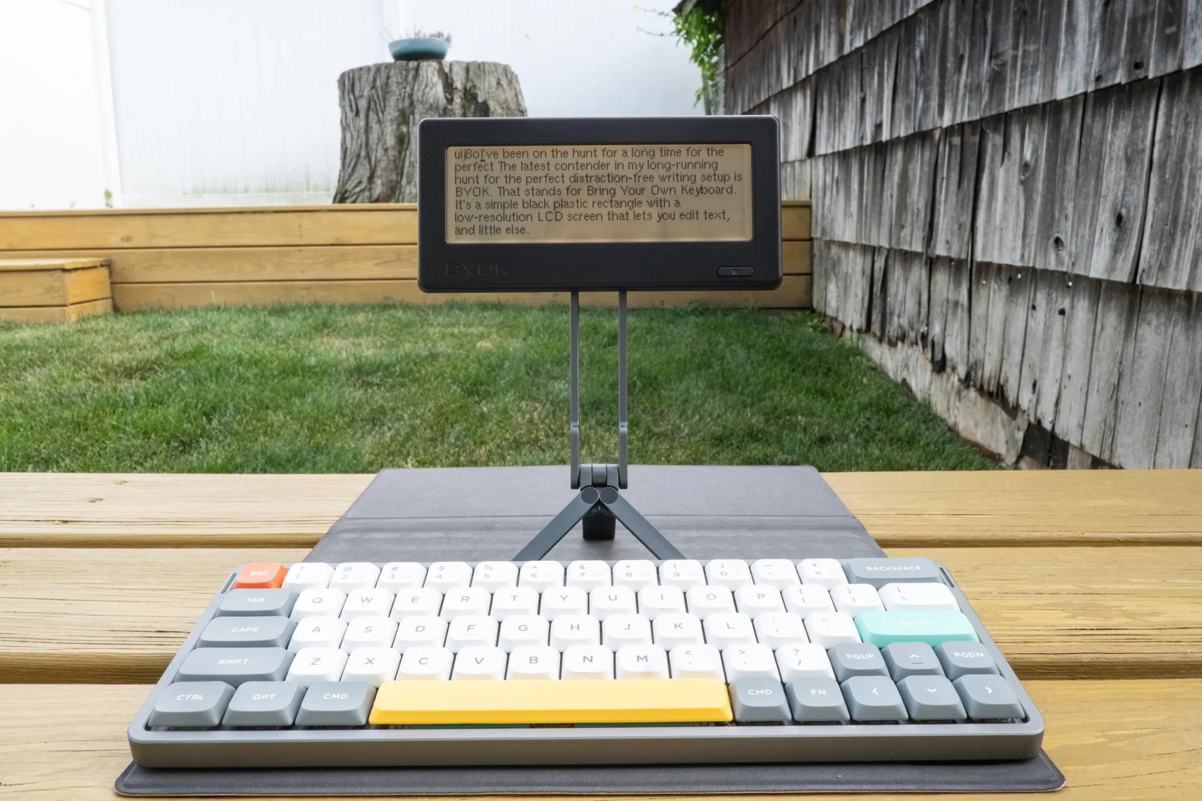The BYOK on a tripod MagSafe stand paired with a NuPhy Air 60 keyboard in a backyard.
